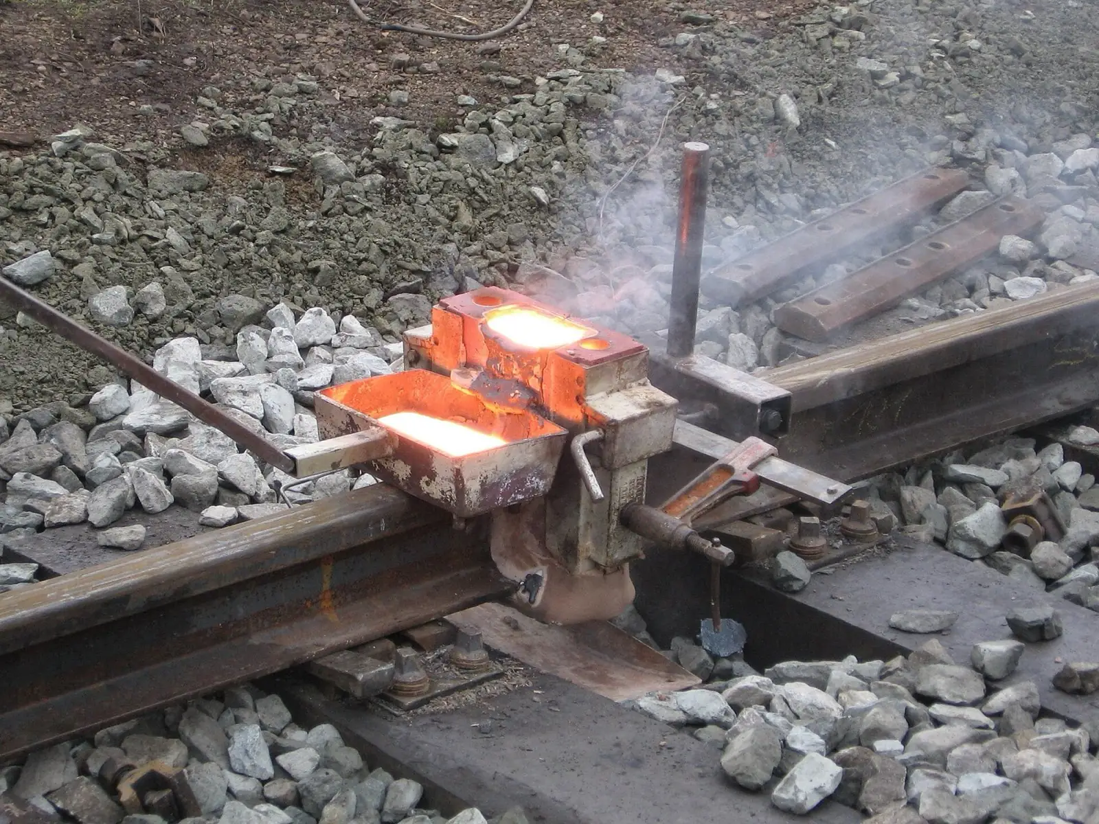 Glowing thermite mould on ballast beside the rail