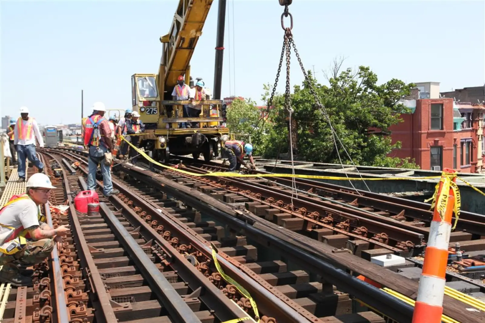 Rail-mounted crane and crew working a track panel into place