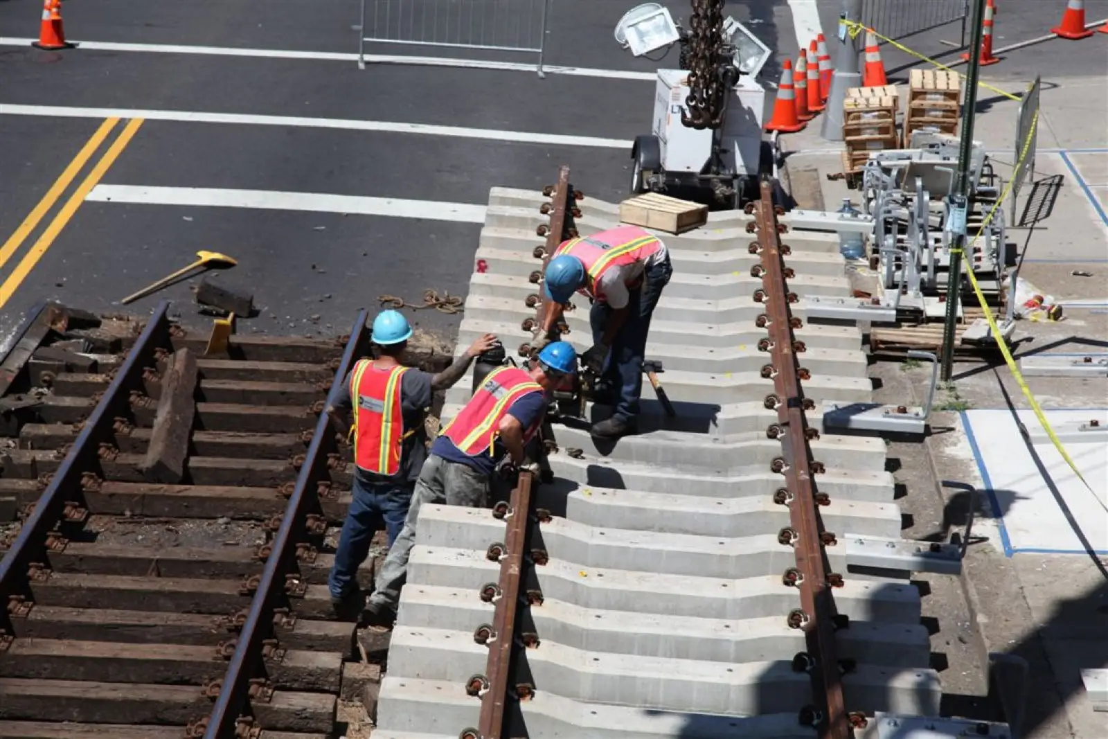 Three track workers coordinating a panel placement beside the rail