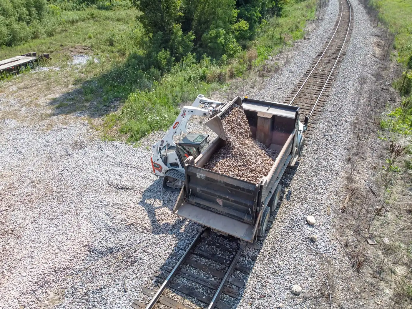 Skid-steer loading ballast into a rail-mounted dump on single track